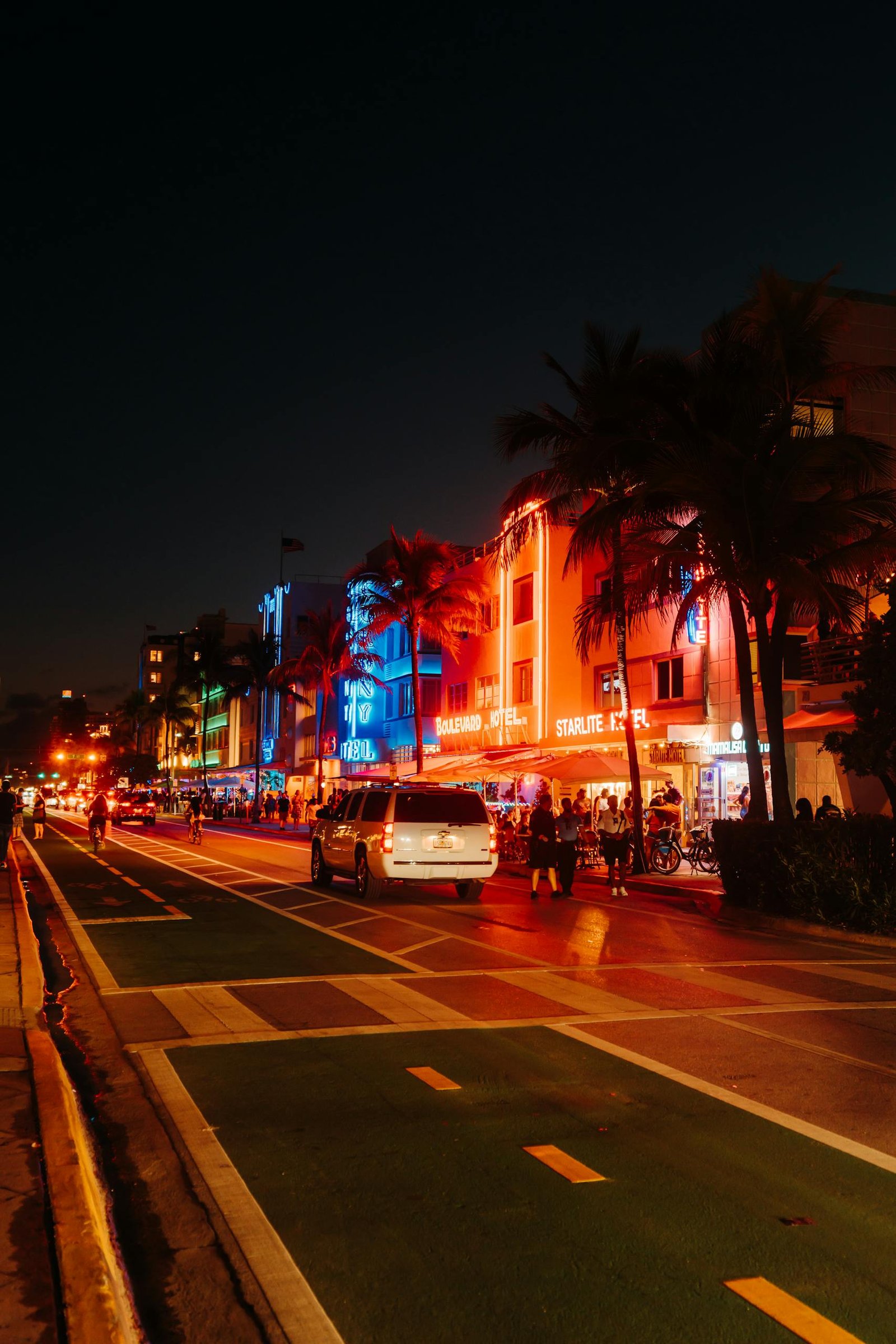 Colorful neon-lit Miami Beach street at night with lively city atmosphere.