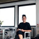 Confident young professional woman enjoying a coffee break in a modern office environment.